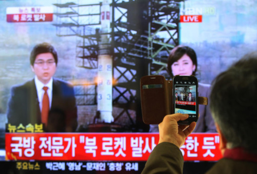 South Korean man uses his smartphone to take a television screen reporting a news about North Korea's rocket launch.