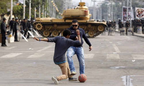 Protesters play with a ball in front of a tank securing the area around the presidential palace in Cairo.