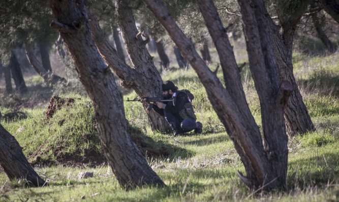 A Free Syrian Army fighter aims his weapon during heavy clashes with government forces.