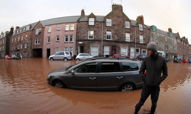 A man stands beside his car in Stonehaven after it was left stranded in the street when the River Carron burst its banks.