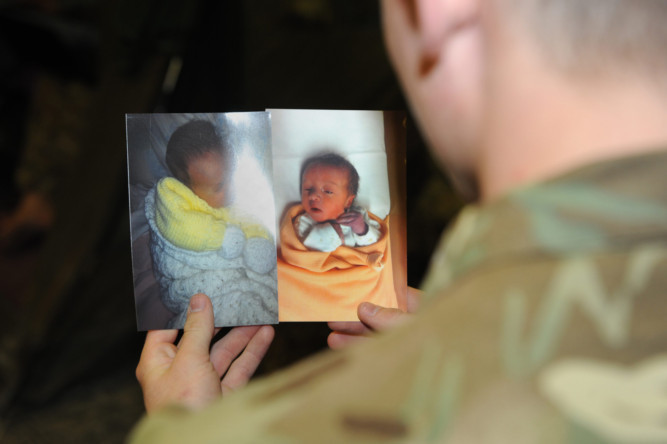 Private Billy Sutherland looks at pictures of his son Bobby James (below), who he finally  got to hold last month after his Afghanistan duty.