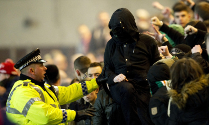 A policeman deals with Celtic supporters at Dens on Wednesday.