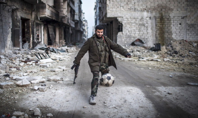A rebel plays football in the Saif al-Dawiah neighbourhood of Aleppo.