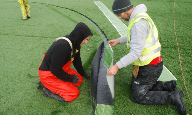 Staff at McDiarmid Park laying the new all-weather pitch.