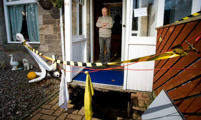 Mr Winton stares down into the hole outside his front door.