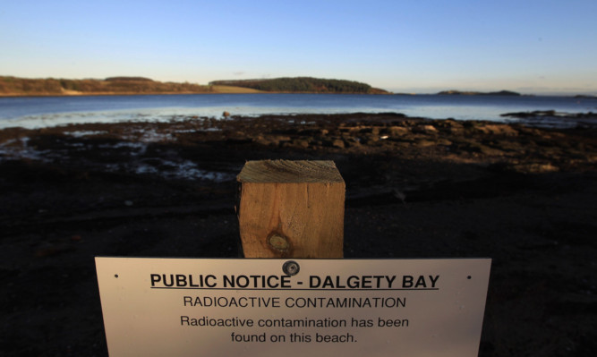 DALGETY BAY, SCOTLAND - NOVEMBER 22:  A public notice warns people of radioactive contamination at Dalgety Bay beach on November 22, 2011 in Dalgety Bay, Scotland. Scientist have warned that unless action is taken to clean up the stretch of shoreline that the beach could become the first stretch of radioactive contaminated land in the United Kingdom.  (Photo by Jeff J Mitchell/Getty Images)