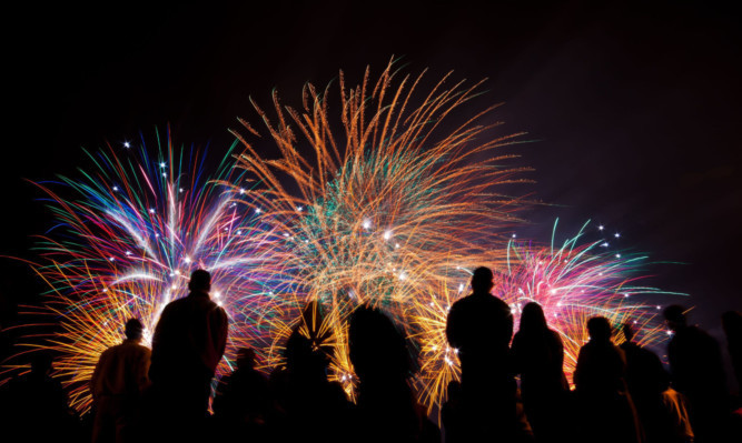 A crowd watches a fireworks display.