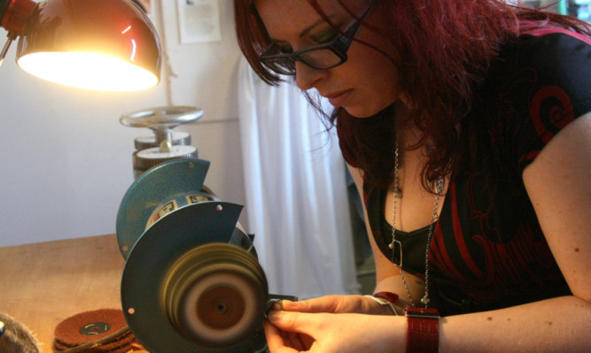 Pictured in her studio is Genna Delaney, jewellery designer.   Genna polishing one of her pieces.