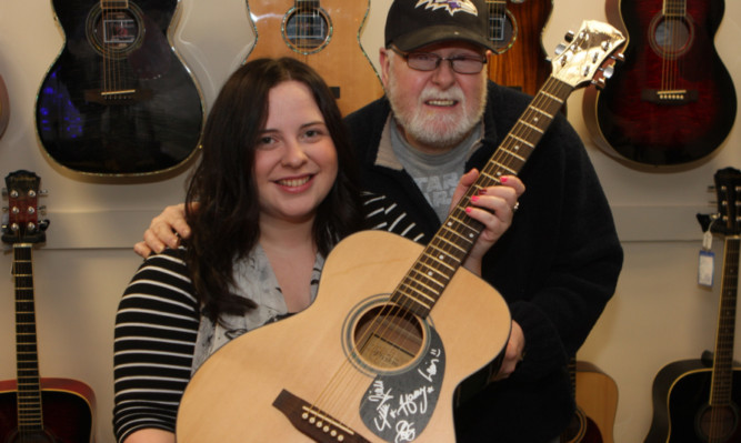 Erin Mowatt shows off her One Direction autographed guitar won at Abbey Music in Arbroath.