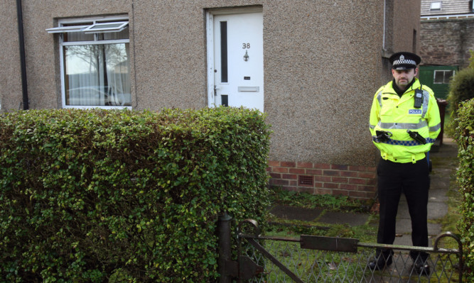 A police officer stands outside the home where Mr Auchterlonie died.