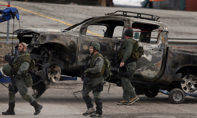 Armed officers beside a burned-out pickup truck which belonged to suspect Christopher Dorner.