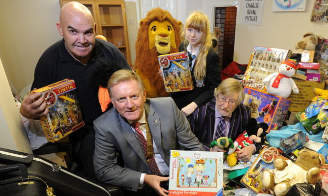 Charlie (left) with Robert Dunn (president of the Rotary Club of Dundee), Emily Irvine and John Irvine (Rotary Club of Dundee community services chairman) and just some of the toys that have been collected.