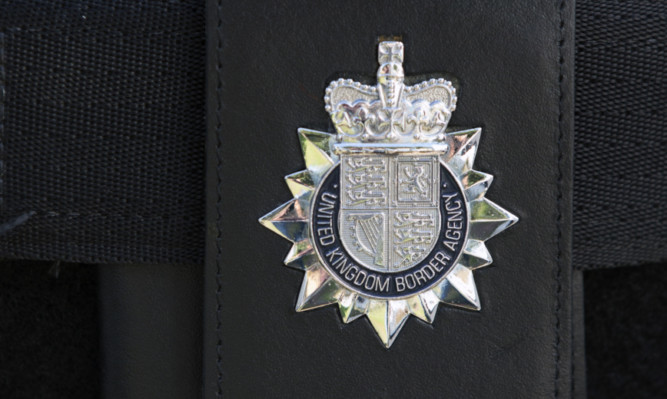 SLOUGH, ENGLAND - JULY 29:  A UK Border Agency crest on the uniform of a Home Office Immigration Enforcement officers as they take part in a raid on a property to detain suspected illegal immigrants on July 29, 2014 in Slough, England. Arrested individuals, who are suspected of residing in the UK illegally, are taken to an immigration detention facility pending their removal from the UK. The Government has announced it is to reduce the time EU migrants without realistic job prospects are able claim benefits from six to three months.  (Photo by Oli Scarff - WPA Pool /Getty Images)