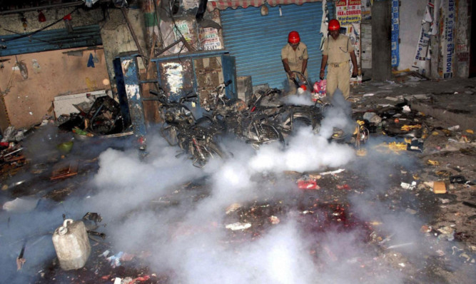 Firemen try to douse the fire at the site of a bomb blast in Hyderabad.