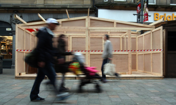 Shoppers pass one of the wooden cabins that were erected in front of shops in Perth city centre.