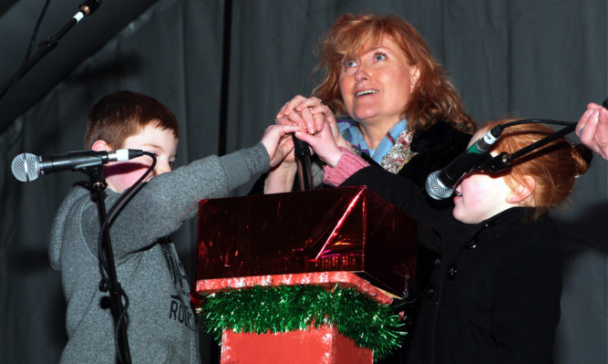 Eddi Reader gets help from two children to turn on the St Andrews lights and students Alice Lecointe and Sean McDonald with Byre Youth Theatre members.
