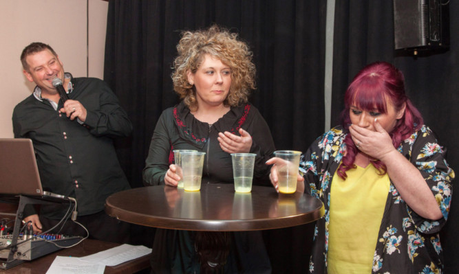 Lois Laird and DJ and host David Eggie look on as Wendy Milne eats her grub.