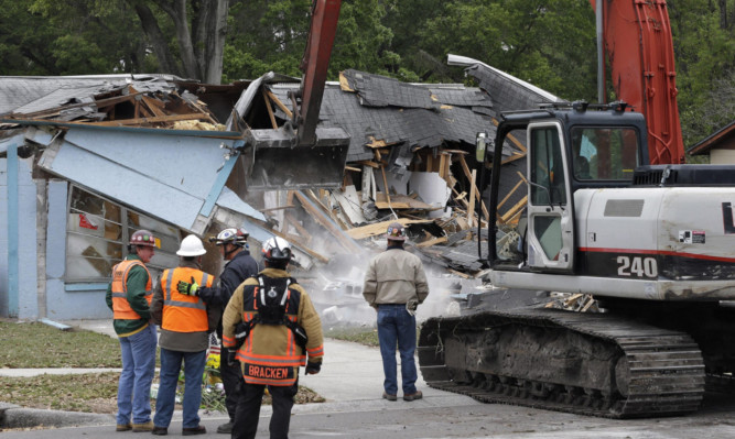 Demolition experts watch as Jeff Bush's home is demolished.