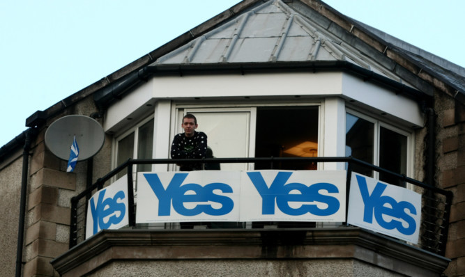 Jason Brown on the balcony of his flat on Caledonian Road in Perth, with his highly visible Yes banners. He will now take them down.