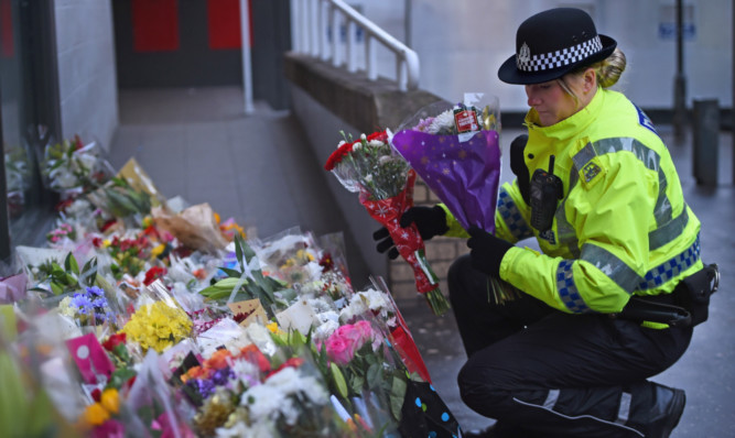 A Police officer lays floral tributes near to the scene of  the bin lorry crash in Glasgow.