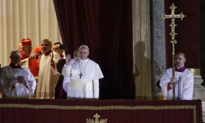 Pope Francis waves to the crowd from the central balcony of St. Peter's Basilica at the Vatican.