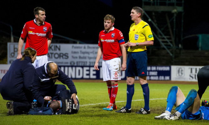 James McPake (left) receiving treatment during the game with Ross County.