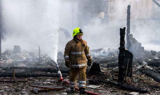 A firefighter in the burned-out remains of the Spittal of Glenshee Hotel.