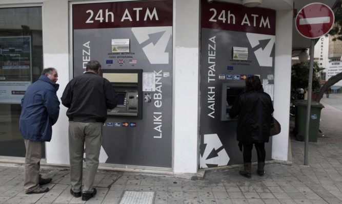 Cypriots use the ATM machines outside of a closed Laiki Bank branch in capital Nicosia.