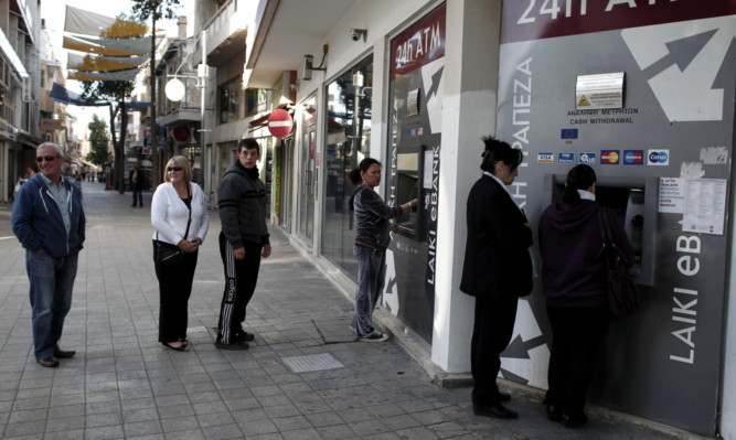 People wait to use the ATM machines outside a closed Laiki Bank branch in capital Nicosia.