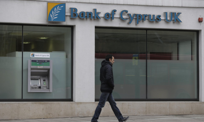 A man walks past a Bank Of Cyprus UK branch in north London.