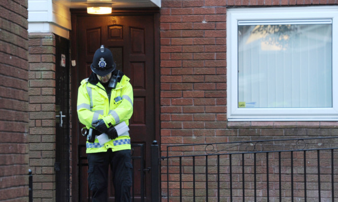 A police officer stands outside the front door of the house where the attack took place.