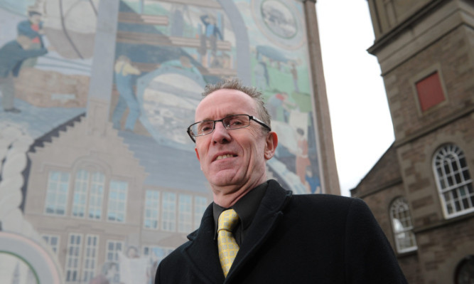 Councillor Fraser Macpherson next to the fading mural on the gable end of a building on St Peter Street.