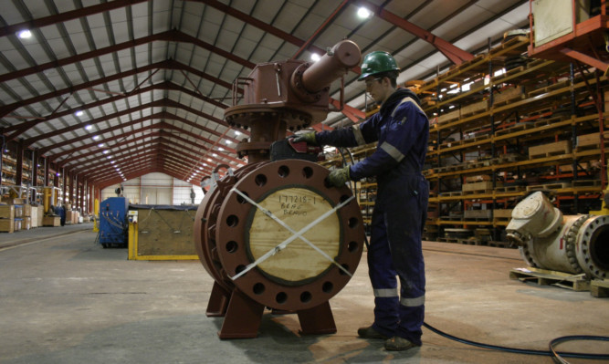 A Scores employee inspecting a valve