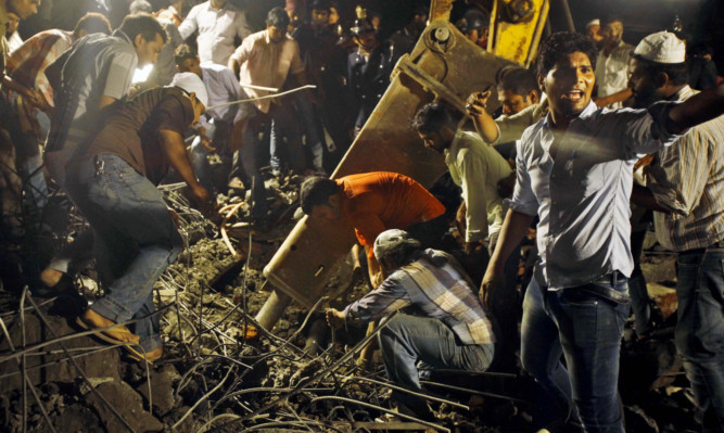 Rescue workers search for trapped people after a building collapsed in Thanei, India.