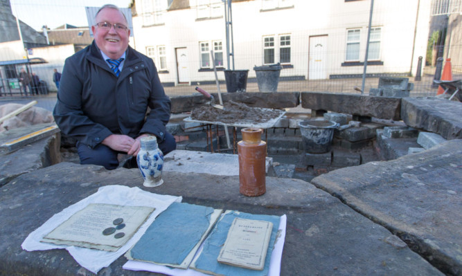 Kincardine Community Council chairman Sandy Brown alongside the artefacts from an unearthed time capsule discovered under the towns market cross during work.