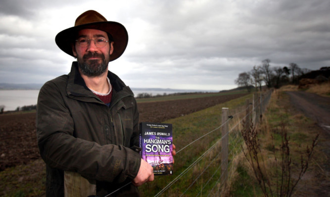 James Oswald on his farm with one of his popular Detective McLean novels.
