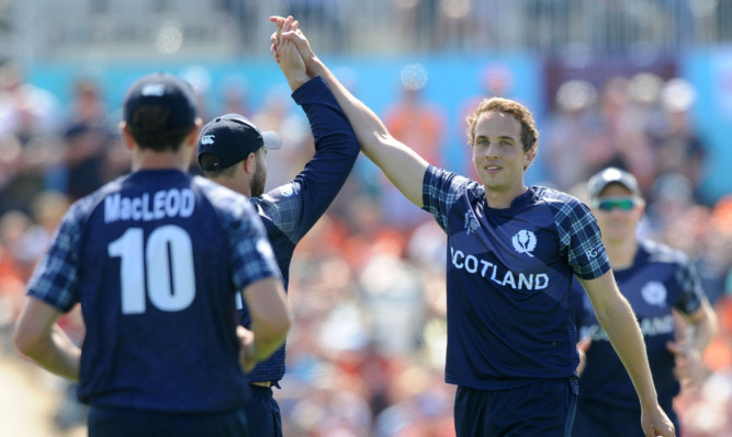 Scotland's Josh Davey, right, is congratulated by teammates after taking a wicket.