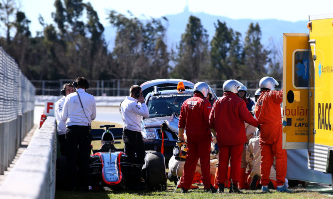 Fernando Alonso receives medical assistance after crashing during day four of Formula One Winter Testing at Circuit de Catalunya.