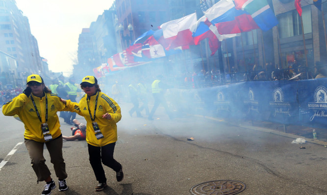 Race officials at the scene moments after the main blast, as one runner is floored by the shockwave.