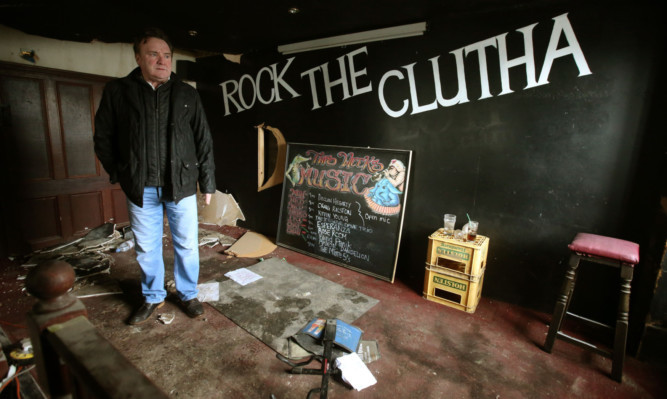 Owner Alan Crossan of the Clutha bar in Glasgow stands on the stage where the band played on the night a police helicopter crashed into the bar.