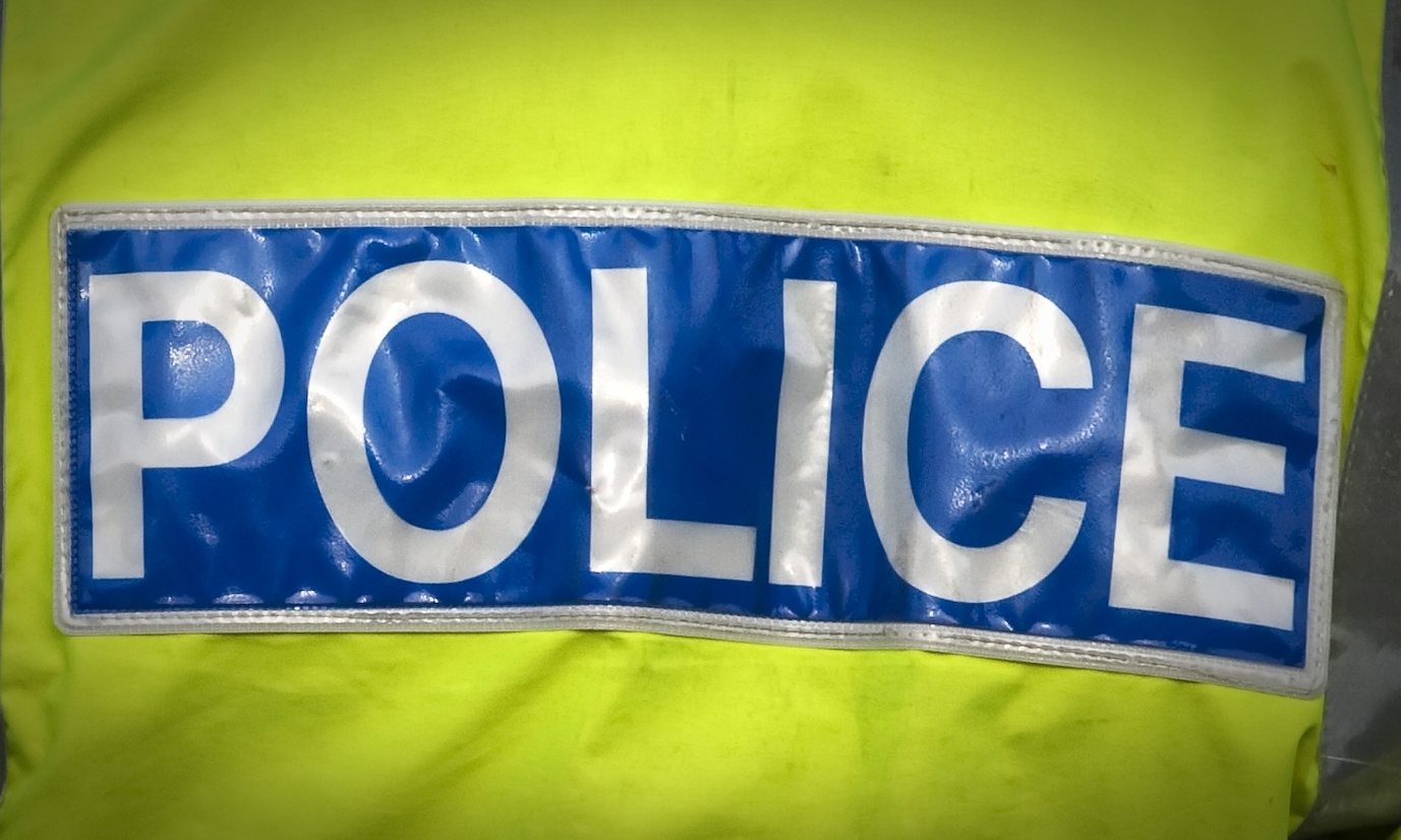 Shot of the back of a police officer's jacket with the word police written across the back