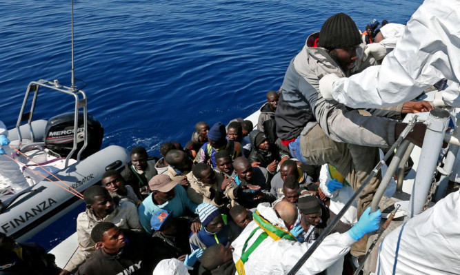 Members of an Italian police unit rescue migrants off the Libyan coast after approaching a crowded inflatable dinghy in the Mediterranean Sea on Wednesday.