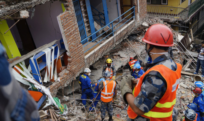 Nepalese and Chinese rescue team look for the body of the earthquake victim from a debris of a building at Balaju in Kathmandu.