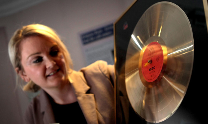 Museum assistant Ruth Nelson with a rare, signed Flick of the Switch gold disc.
