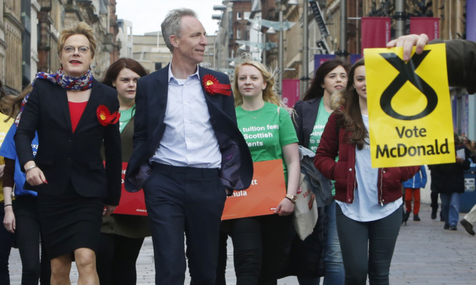 A protester holds an SNP poster as comedian Eddie Izzard and Scottish Labour leader Jim Murphy are on the General Election campaign trail in Glasgow.