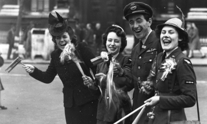 An RAF officer, two members of the Womens Royal Air Force and a civilian celebrate the news of victory in London.