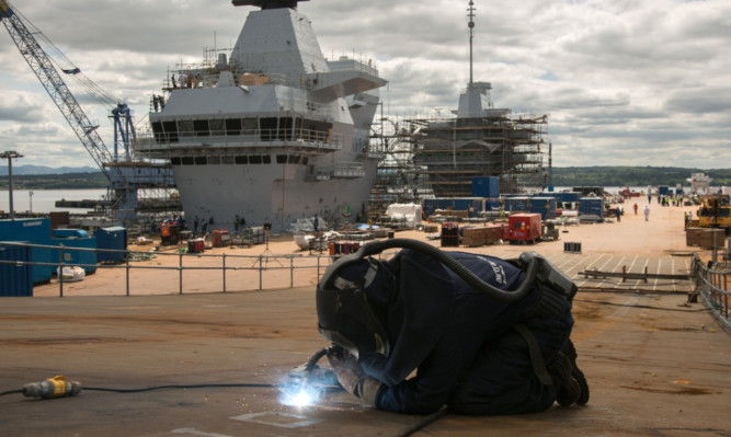 A construction worker on the flight deck of HMS Queen Elizabeth aircraft carrier at Rosyth dockyard.