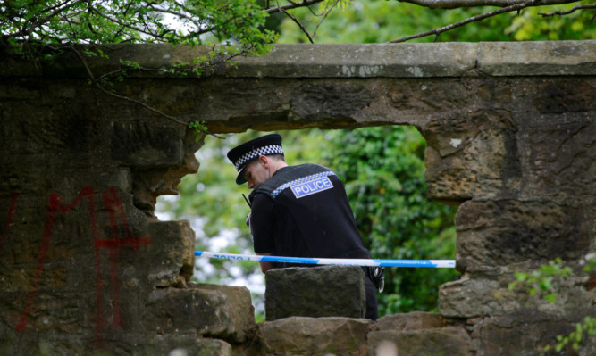 Police guard a hole in the wall at Craigton Cemetery, in Glasgow, where an eight-year-old boy died and two ten year-olds have been injured in an incident inside the cemetery.