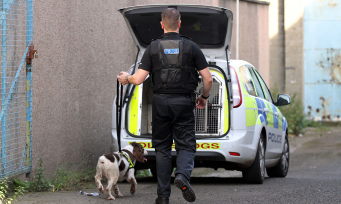 A police dog handler at the scene of a raid in Dundee.