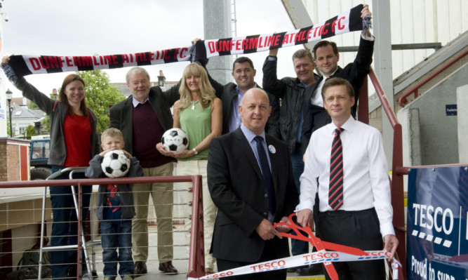 Supporters look on as Tony McElroy from Tesco, left, and Ross McArthur cut the ribbon for the new seating area.